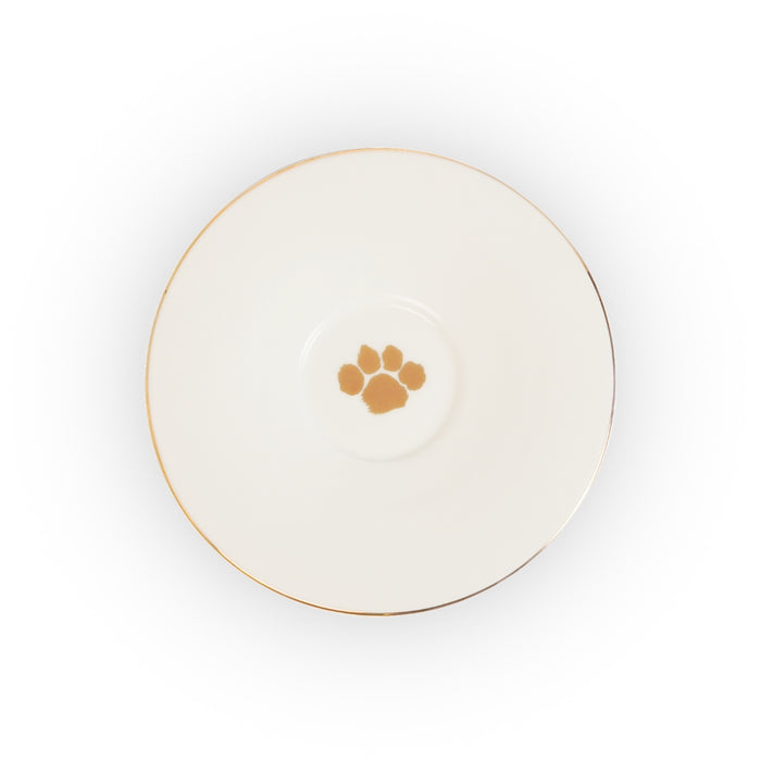 A white ceramic plate or saucer with a thin gold rim and a small gold paw print motif in the center, shown from a top-down view on a white background.