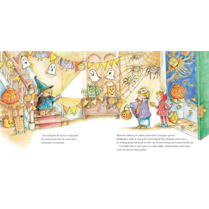 A full-page children's book illustration spread showing a cozy Halloween scene with Paddington bear and children, pumpkins, ghosts, banners, and warm interior decor. The page includes two blocks of text at the bottom.