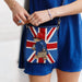 A travel wallet with a woven tapestry design featuring Paddington bear wearing a hat on a Union Jack background, being held by a person wearing a blue dress.