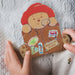 Puxxle jigsaw bear cutout with travel-themed stickers held by a person on a textured fabric background
