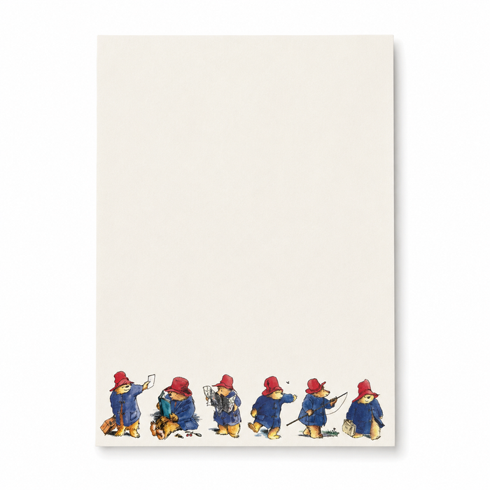 An off-white rectangular piece of writing paper featuring a row of Paddington Bear illustrations along the bottom edge, shown against a clean white background.
