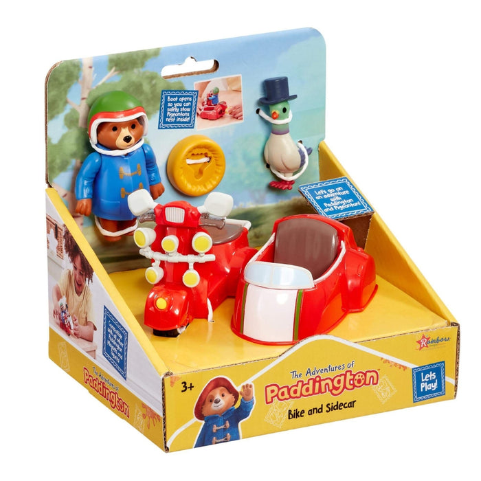 TV Paddington-themed toy set in its retail packaging, featuring a red sidecar-style toy car, a red scooter with white details, a blue Paddington bear figure, and a pigeonton figure on a yellow-and-blue display box.