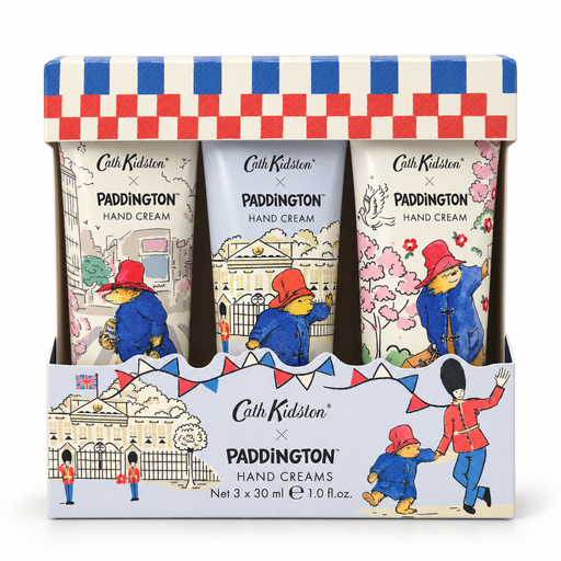 A boxed set of three Cath Kidston x Paddington hand creams in a decorative display tray. The packaging features a red, white, and blue checkered top, and the three cream tubes are illustrated with Paddington in red and blue outfits against city and garden backgrounds.