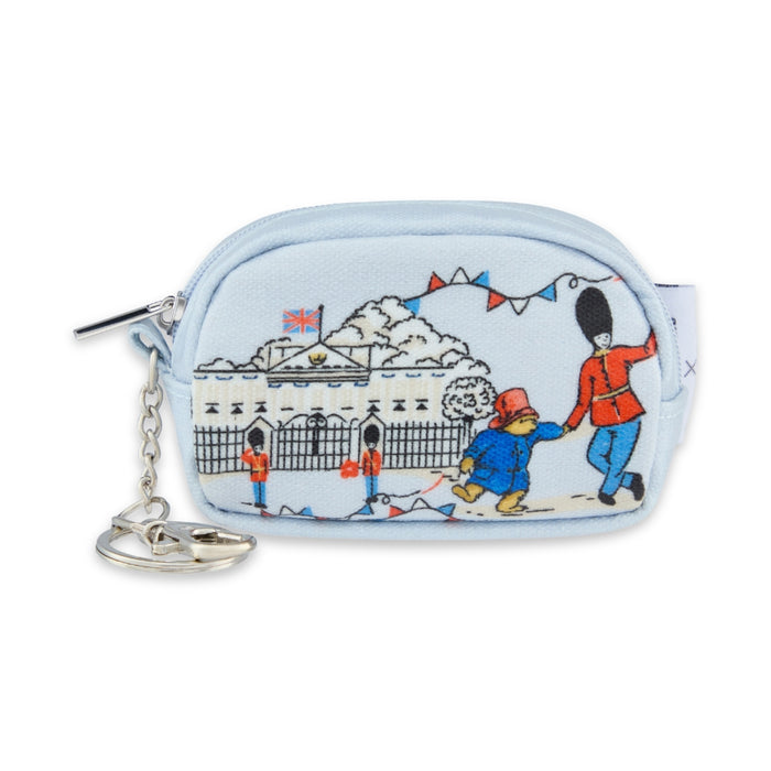 A light blue zippered coin purse featuring a cartoon illustration of Paddington Bear and a London guard, with a silver keychain attached on a white background.