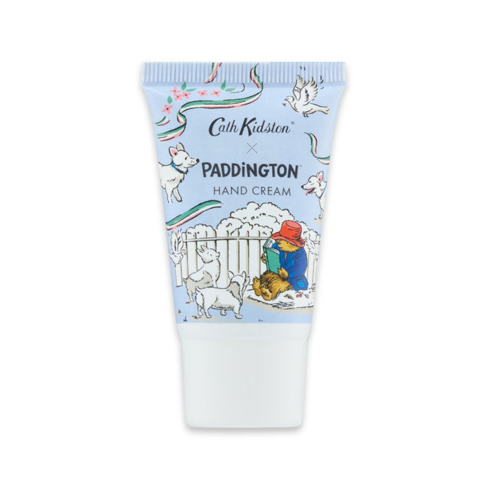 A squeeze tube of Cath Kidston x Paddington Hand Cream, featuring a light blue and white park-themed illustration of Paddington Bear, foxes, and other animals  on a white background.