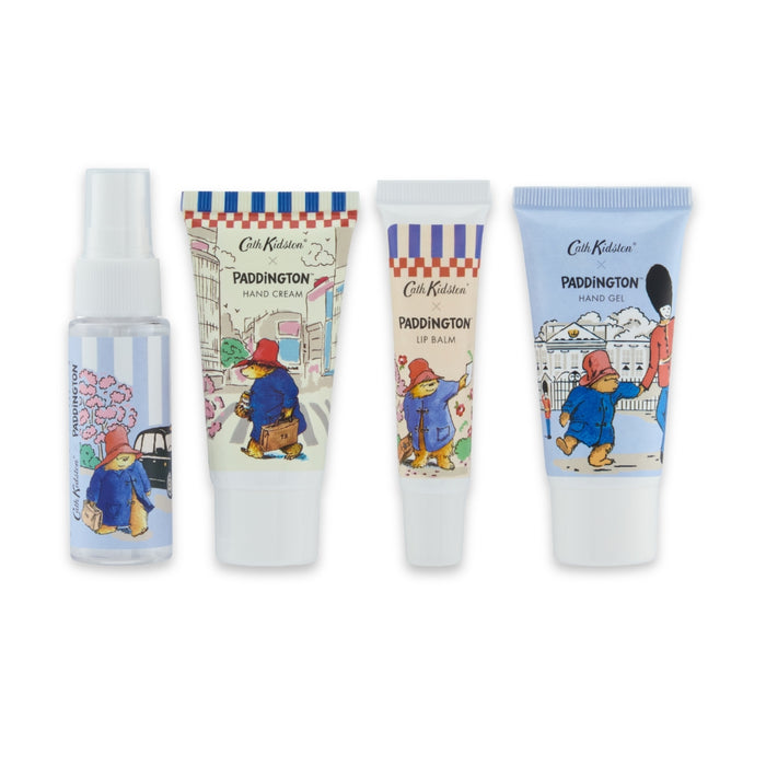 A set of four Paddington-themed toiletry products from Cath Kidston, including a hand cream tube, a lip balm tube, a hand gel tube, and a body mist spray bottle, all featuring illustrations of Paddington Bear on a white background.