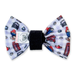 A novelty pet bow tie featuring a white fabric printed with colorful cartoon paddingtons and red telephone booths, secured with a black elastic band.