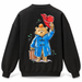 A black crewneck sweatshirt shown from the back, featuring a large graphic print of Paddington Bear in a blue duffel coat holding a red hat and a brown suitcase, with an orange on his head.