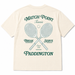 An off-white short-sleeve t-shirt showing the back, which features a dark green graphic print with crossed tennis rackets, a tennis ball, and the text 'MATCH POINT Tennis BREAK SERVE Since 1958 PADDINGTON'.