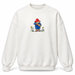 An off-white crewneck sweatshirt featuring a central graphic of Paddington Bear holding a jar of marmalade, with small yellow flowers at his feet, shown against a plain white background.