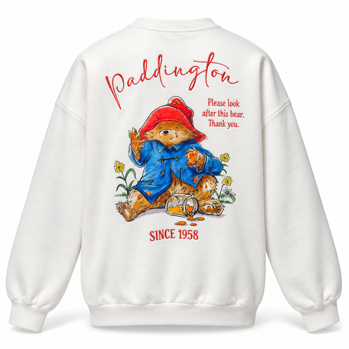 White crewneck sweatshirt shown from the back, featuring a large graphic of Paddington Bear with red text reading 'Paddington' and 'SINCE 1958' on a clean white background.