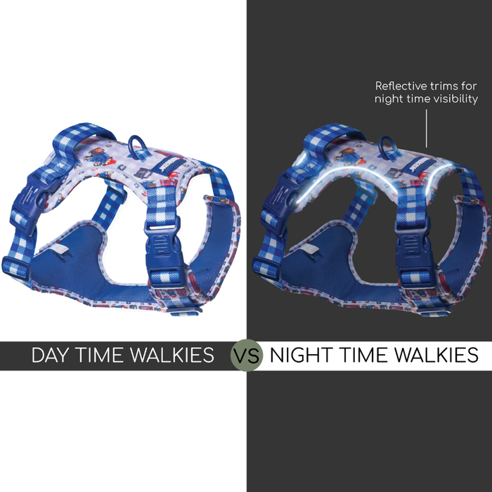 A split comparison showing a blue and white patterned dog harness on a white background on the left, and the same harness on a dark gray background on the right with reflective trim visible. Text at the bottom reads 'DAY TIME WALKIES VS NIGHT TIME WALKIES' and text on the right says 'Reflective trims for night time visibility'.
