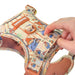 Paddington bear-themed dog harness being adjusted by a hand on a white background