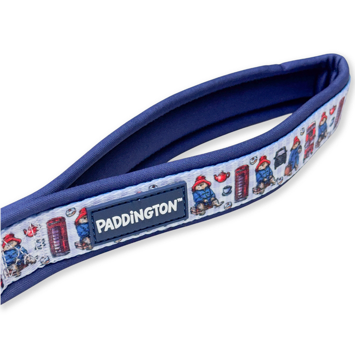 A padded navy blue strap with a white printed border featuring Paddington Bear illustrations and a central navy patch with the Paddington brand name.