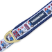 A close-up of a Paddington-themed dog collar on a white background, featuring a navy blue fabric strap with a white printed pattern of Paddington Bear, red telephone booths, and a gold metal D-ring clasp.