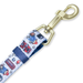 A close-up of a pet leash featuring a white woven fabric with a colorful cartoon pattern of red buses, blue cars, and characters, attached to a gold-toned metal swivel clasp.