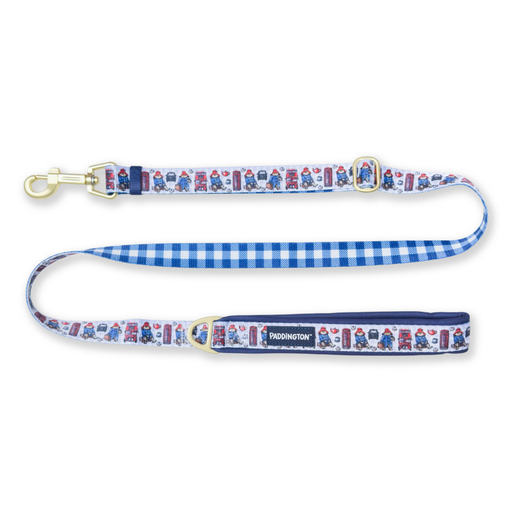 A dog leash featuring a blue and white gingham patterned strap, a white fabric body printed with a repeating red and blue London London bus and telephone box motifs, and brass hardware.