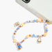 A colorful beaded phone strap with paddington bear character charms, shown attached to a clear smartphone case on a white background.