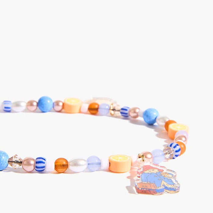 A beaded phone charm strap with pastel blue, orange, pink, and white beads, featuring a small illustrated paddington charm on a gold chain, set against a plain white background.