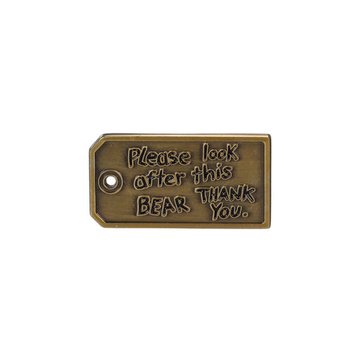 A rectangular pin badge with the text 'Please look after this bear. Thank you.' in a bronze tone.