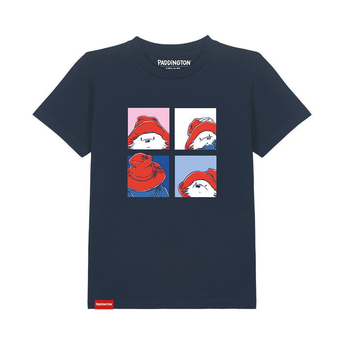 A navy blue short-sleeve t-shirt featuring a graphic of Paddington Bear in a four-panel comic style. The graphic shows Paddington wearing his signature red hat, with the words 'PADDINGTON' printed inside the collar and a small red tag near the bottom left hem.