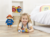 A little girl playing with Paddington bear toy figurines in a white bedroom and rainbow pillow