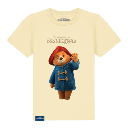 A butter cream kids' T-shirt with a graphic of Paddington Bear in a red hat and blue coat on a yellow background, with the text 'The Adventures of Paddington'.