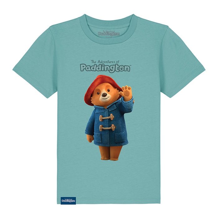 A blue kids' T-shirt with a graphic of Paddington Bear in a red hat and blue coat on a teal background, with the text 'The Adventures of Paddington'.