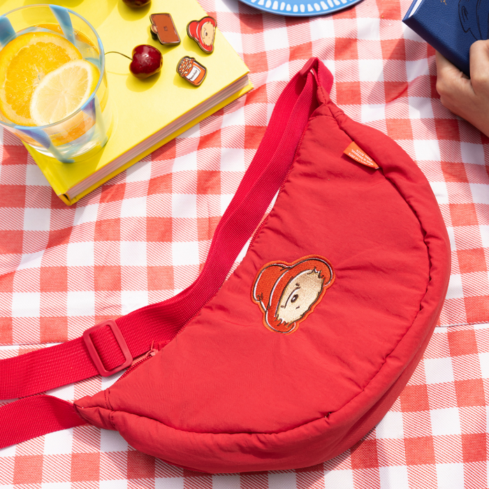 Red crossbody bag with a cartoon paddington bear character on a red and white checkered tablecloth.
