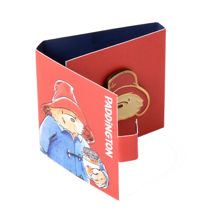 Red box with Paddington Bear illustrations and a brass enamel Paddington badge on a white background