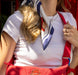 Person wearing a white shirt with a red and blue pattern paddington bear scarf, holding a red bag.