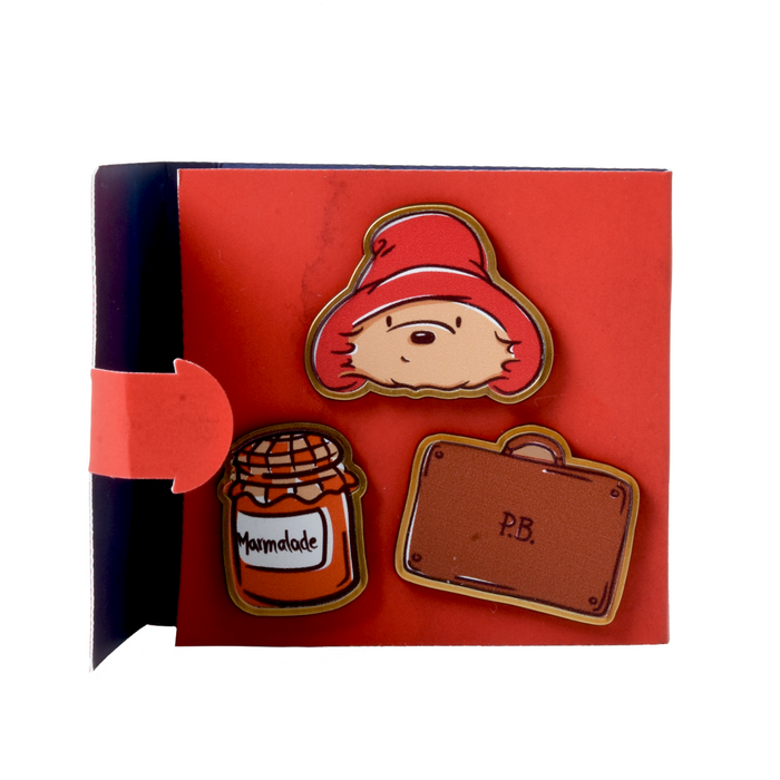 Set of three decorative Paddington bear pins on a red card with a white background