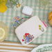 Video of a summer tablescape featuring someone pulling a necklace from a paddington coin purse