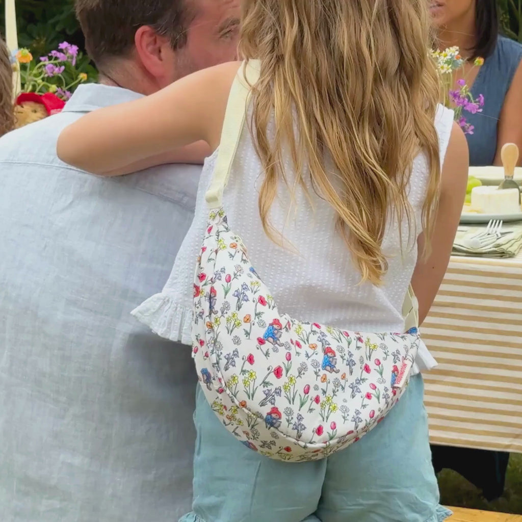 Video of a summer picnic tablescape with a girl wearing a paddington crossbody bag and then  close up of the bag hanging on a washing line in front of a brick wall