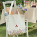 Video of a summer tablescape picnic featuring a white and floral paddington canvas shoulder bag with blue cornflowers and baguettes inside