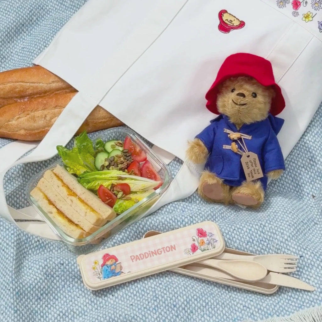 Video of a summer tablescape featuring a paddington picnic cutlery set next to a marmalade sandwich and salad lunch box and someone buttering bread