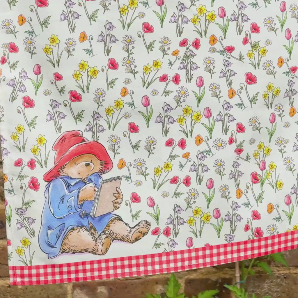 Video of a summer washing line featuring a paddington floral tea towel in front of a brick wall and a close up of the kitchen towel folded on the tablescape